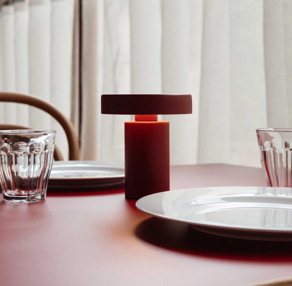 Detailaufnahme einer roten Tischlampe auf gedecktem Tisch.