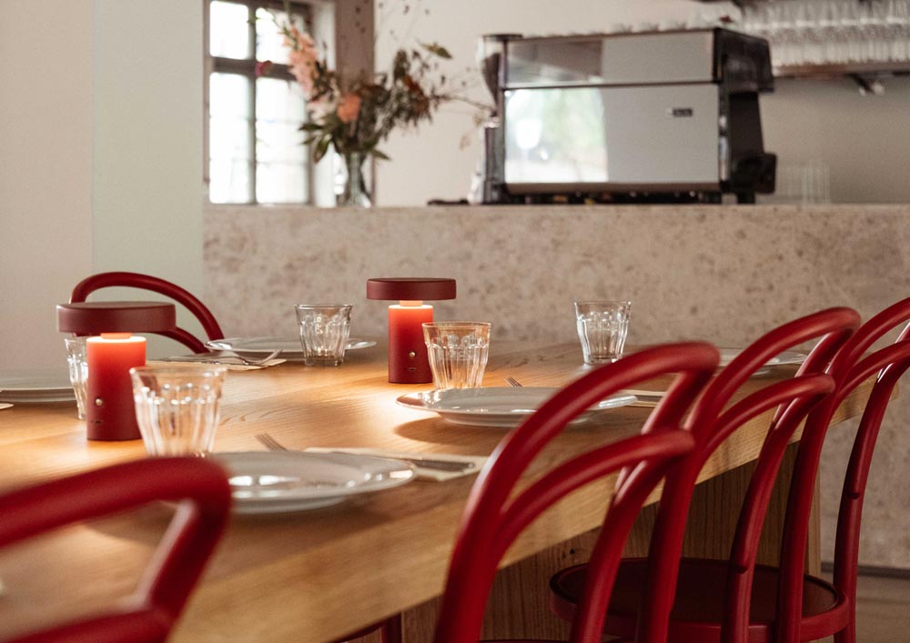 Tisch mit roten Stühlen, gedeckt und Bar im Hintergrund.